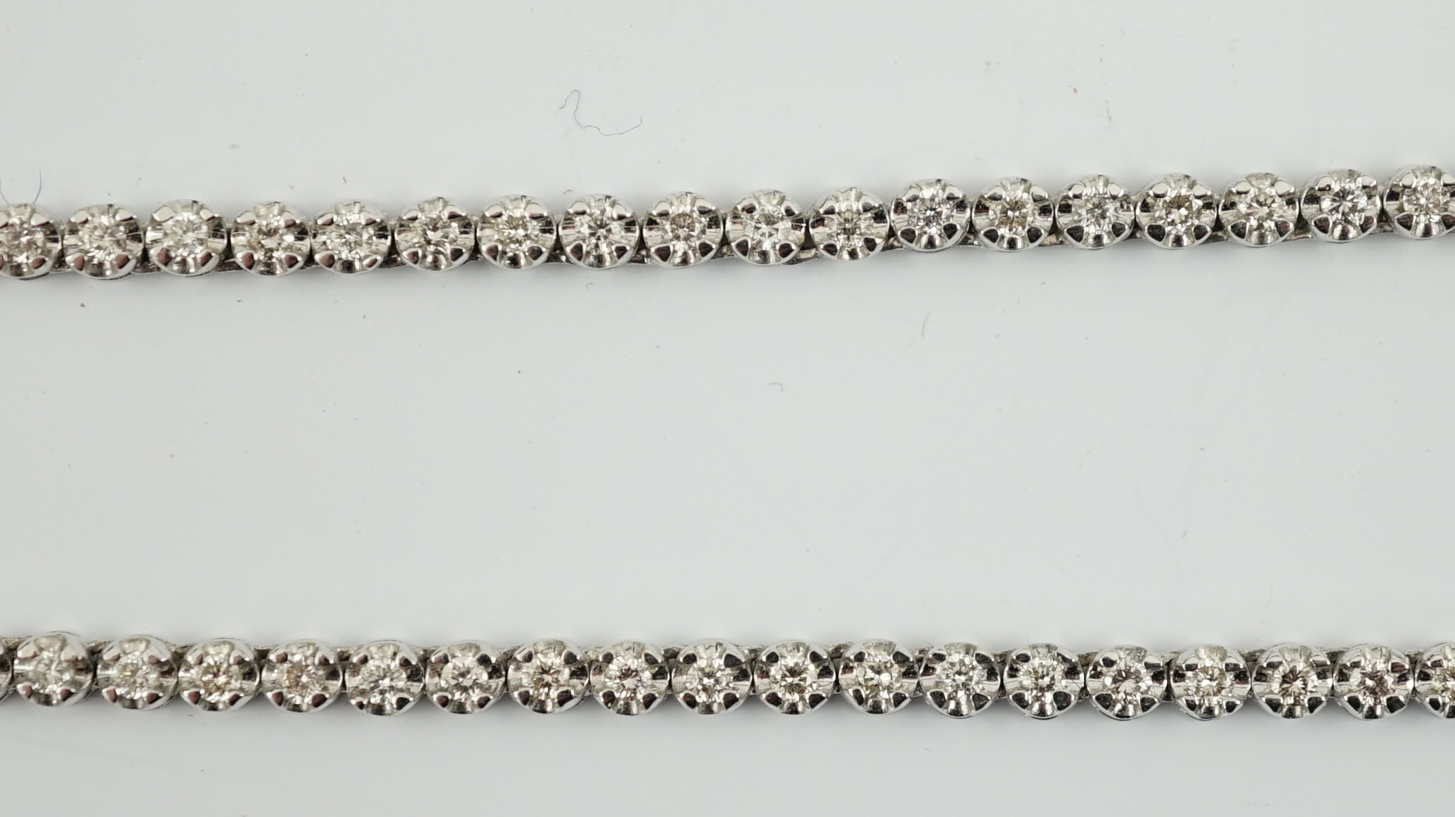 A modern 18k gold and illusion set diamond line necklace, set with diamond chips and five graduated larger stones, 40cm, gross weight 17 grams. Condition - poor to fair (old repair to one link)